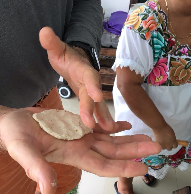 A tortilla being made in the palm of someone's hand in Merida cooking class